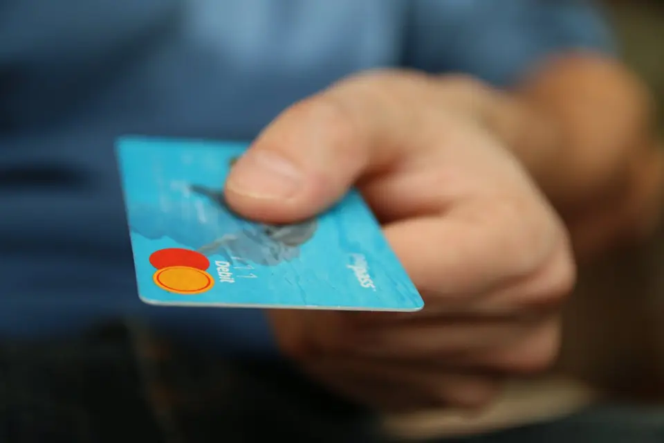 Hand reicht eine Bankkarte zum Bezahlen