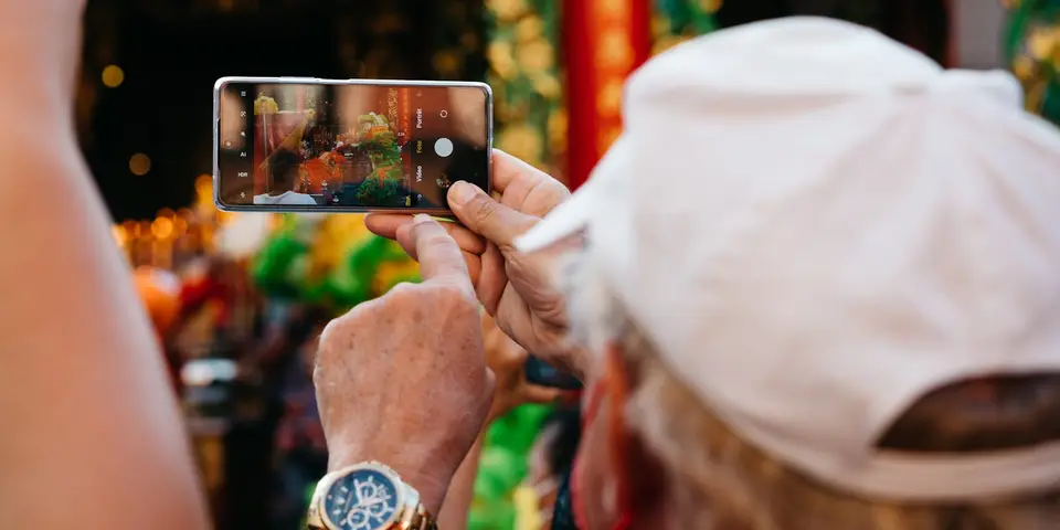 Älterer Mann fotografiert mit seinem Smartphone