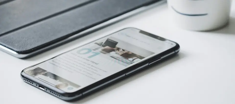 Smartphone liegt neben einem Tablet auf einem hellen Schreibtisch